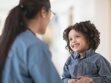 Child smiling at an adult in a blue shirt.