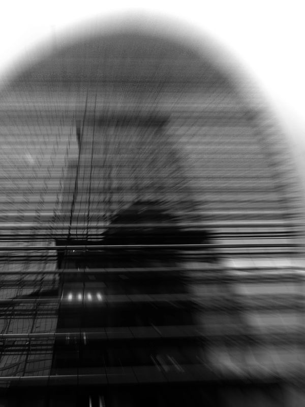 Blurred black and white image of a modern building with a curved roof.