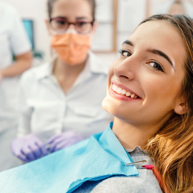 Patient with perfect white teeth and smile satisfied after dental treatment in a dentist office