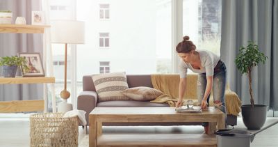 Woman arranging items on a coffee table in a cozy living room.