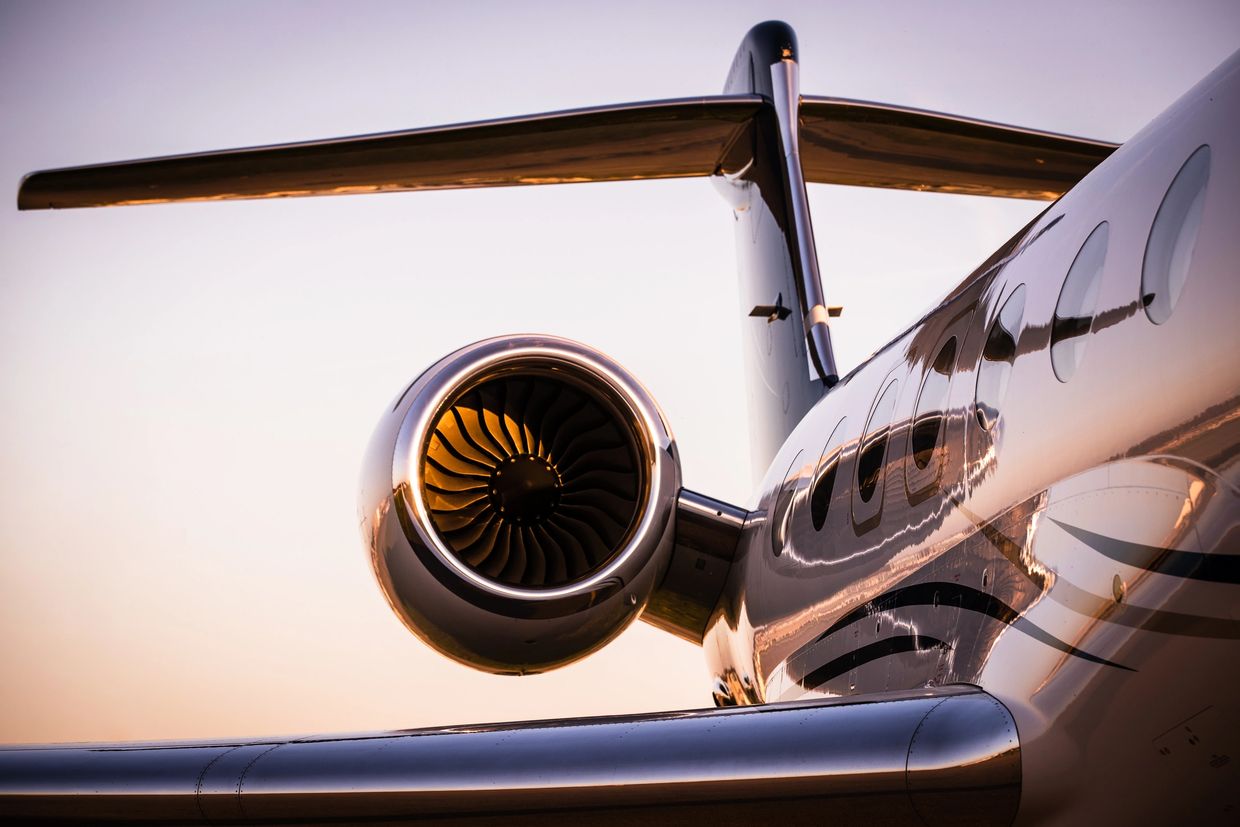 Close-up of an aircraft jet engine and tail at sunset.