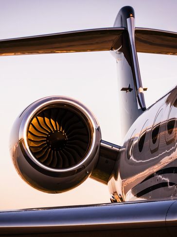 Close-up of a jet engine and wing at sunset on a private jet.