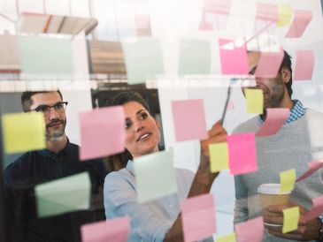 Pessoas discutindo ideias em post-its coloridos.