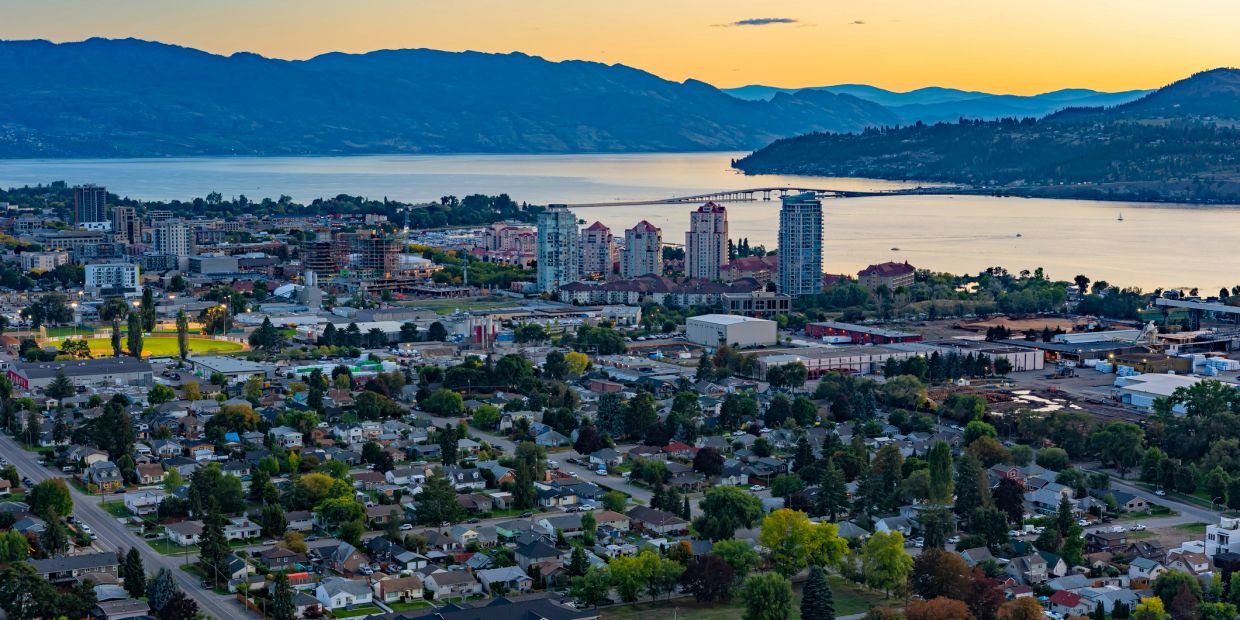 City skyline with mountains and lake at sunset.