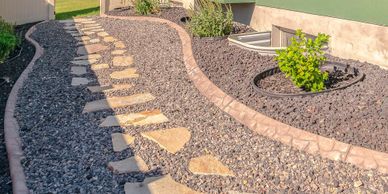 A stone pathway winds through a landscaped garden with gravel and small plants.