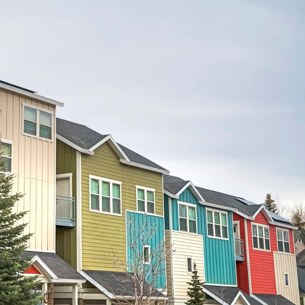 Colorful row of modern townhouses under a cloudy sky.