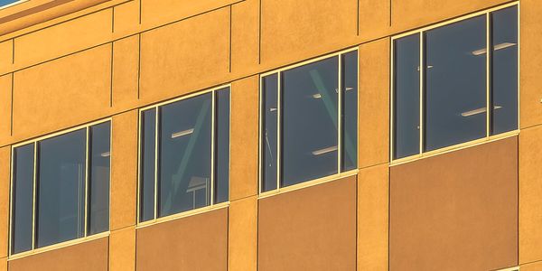 Modern building facade with large glass windows reflecting the sky.