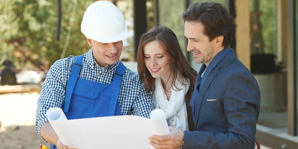 Construction worker showing blueprints to a couple at a building site.
