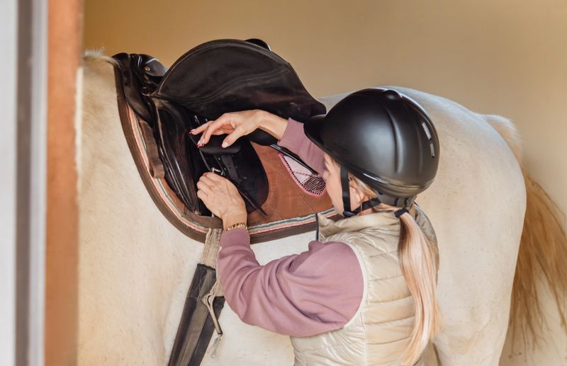Woman saddling horse before ride.