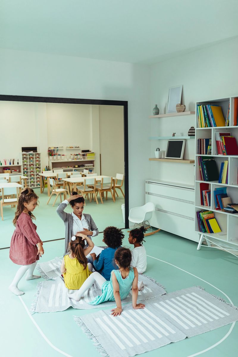 Female teacher reading a story to cute children at kindergarten