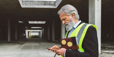 Industrial supervisor in high-vis gear reviewing HR documents on a BC jobsite.
