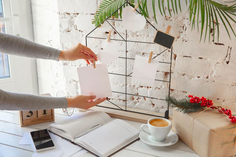 Writes wishes. Dreams of goals plans make a list for writing in notebook. Female hands on a background with wooden calendar, giftbox for New Year, winter holidays and Christmas time. Preparing moodboard.