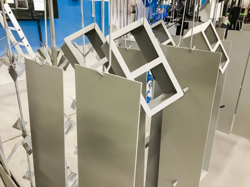 Powder coating line. Metal panels are suspended on an overhead conveyor line. Painting products in an electrostatic field.