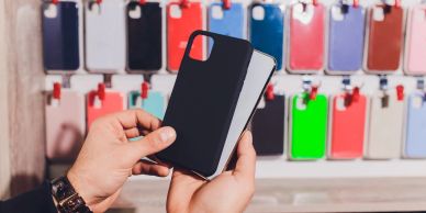 Person holding a black phone case in a store.