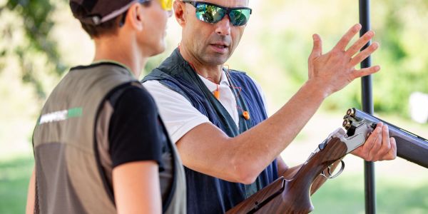 Two men discussing with one holding a shotgun.