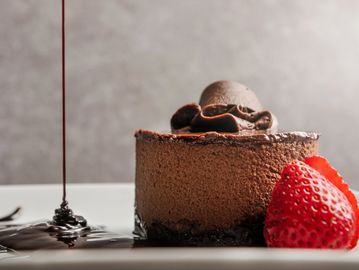 A chocolate mousse cake with a strawberry and chocolate drizzle.