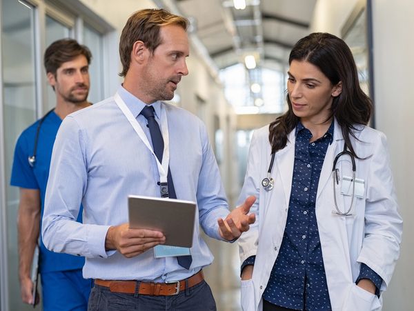 Medical professionals and a visitor discussing in a hospital corridor.