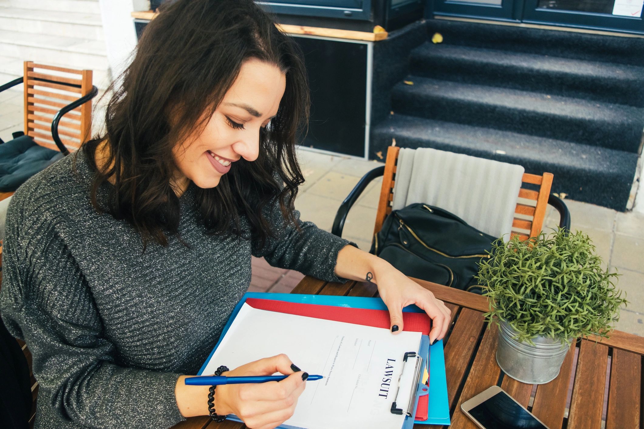 Woman smiling while holding a pen over a lawsuit document.