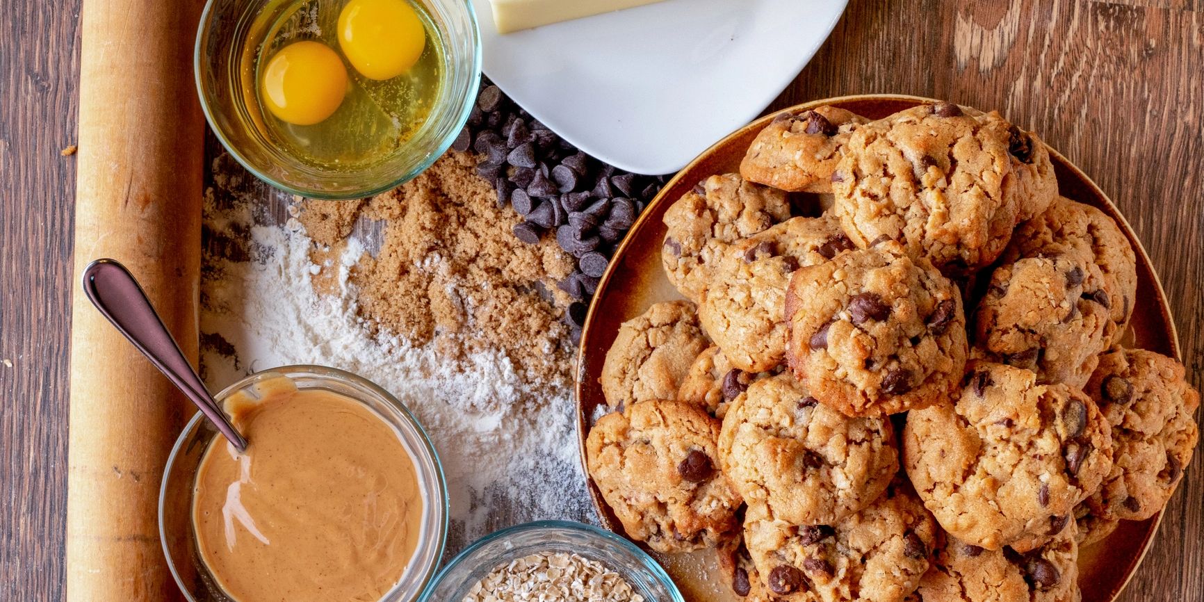 Ingredients and baked chocolate chip cookies on a wooden table.
