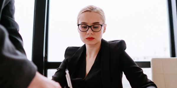 Professional woman in glasses focused on signing documents in office.
