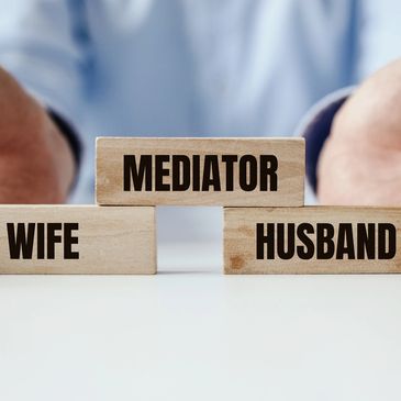 Wooden blocks labeled Wife, Husband, and Mediator symbolizing conflict resolution.