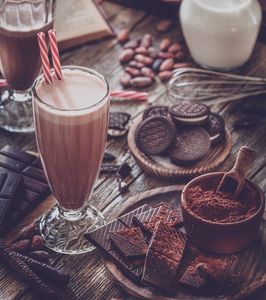 Fresh strawberries dipped in chocolate with white drizzle on a wooden board.