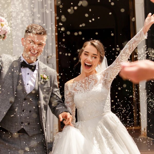 Happy newlyweds celebrating outside with confetti.