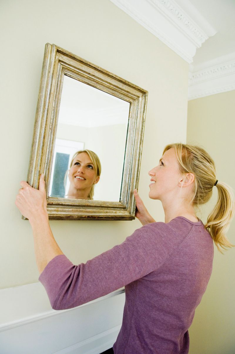 Woman hanging mirror on wall