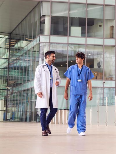 Two medical professionals walking and talking in a modern hospital corridor.
