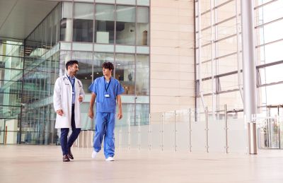 Two medical professionals walking and talking inside a modern hospital.
