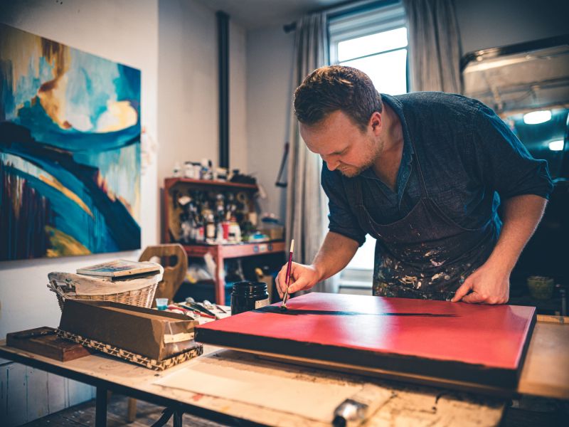Young painter working on his art inside his studio.