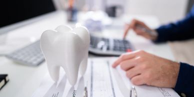 Large model of a tooth on an invoice document with a person working in the background.