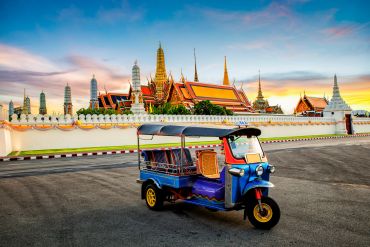 Tuk-tuk in front of a temple at sunset.