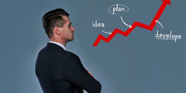 Businessman looking at a rising growth arrow with labels plan, idea, and develop.