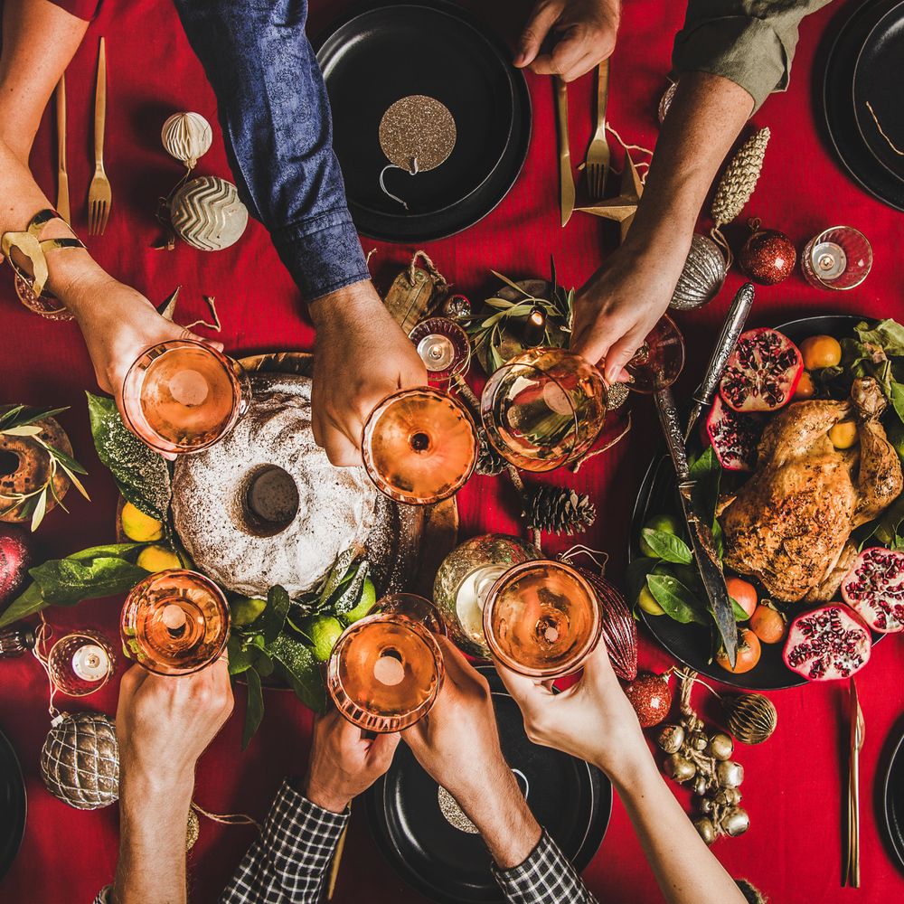 Friends toasting with rose wine over a festive holiday meal.