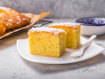 Two pieces of coconut cake on a white plate with a spoon.