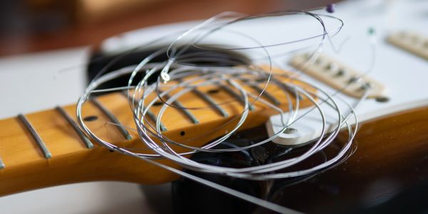Coiled guitar strings resting on an electric guitar's neck and body.