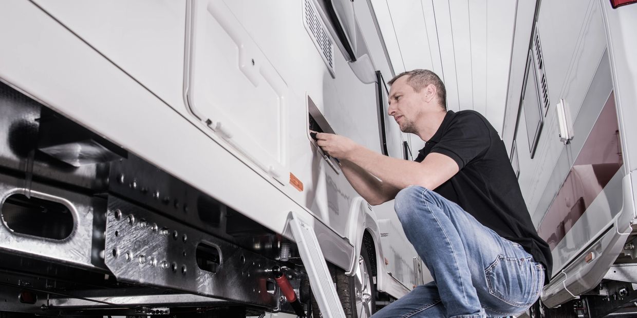Technician working on an exterior compartment of an RV.