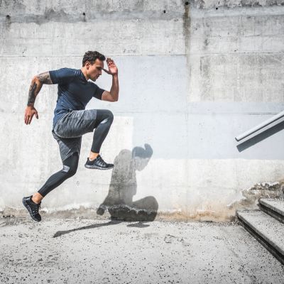 Man jumping outdoors near stairs.