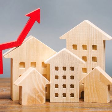 Wooden house models with a red upward arrow.