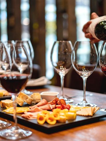 Tábua de queijos e vinhos sendo servida.
