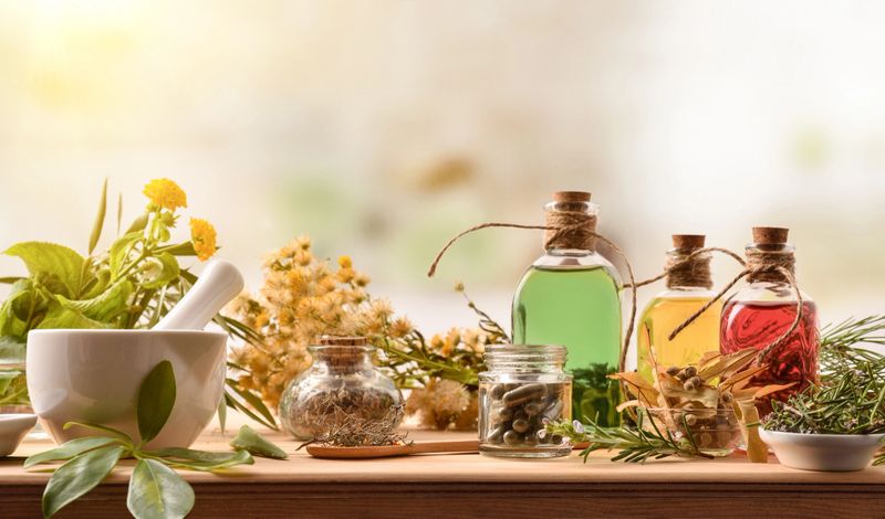 Composition of natural alternative medicine with capsules, essence and plants on wooden table in rustic kitchen. Front view. Horizontal composition.
