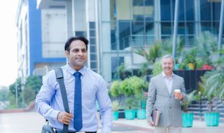Two men walking outside an office building.