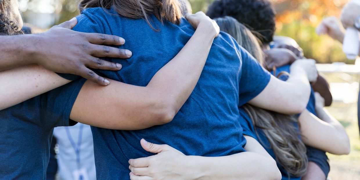 Group of people in a close, supportive hug.
