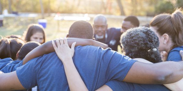 A group huddles together outdoors, showing team spirit and unity.