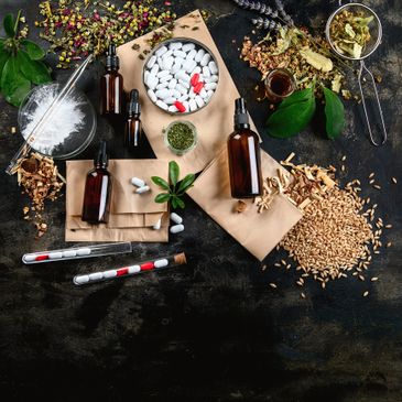 Various herbal medicine ingredients and tincture bottles arranged on a dark surface.