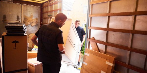 Two men moving a door inside a moving truck.