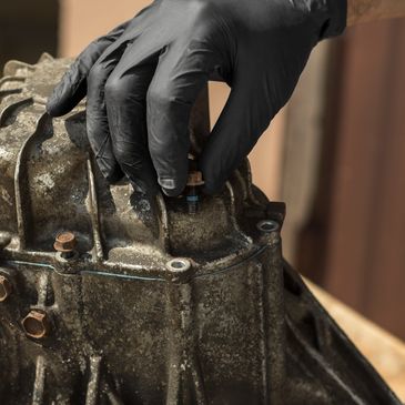 Hand in glove working on engine part.