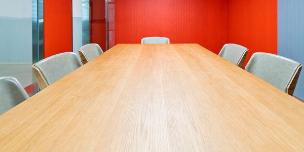 Empty modern conference room with wooden table and gray chairs.