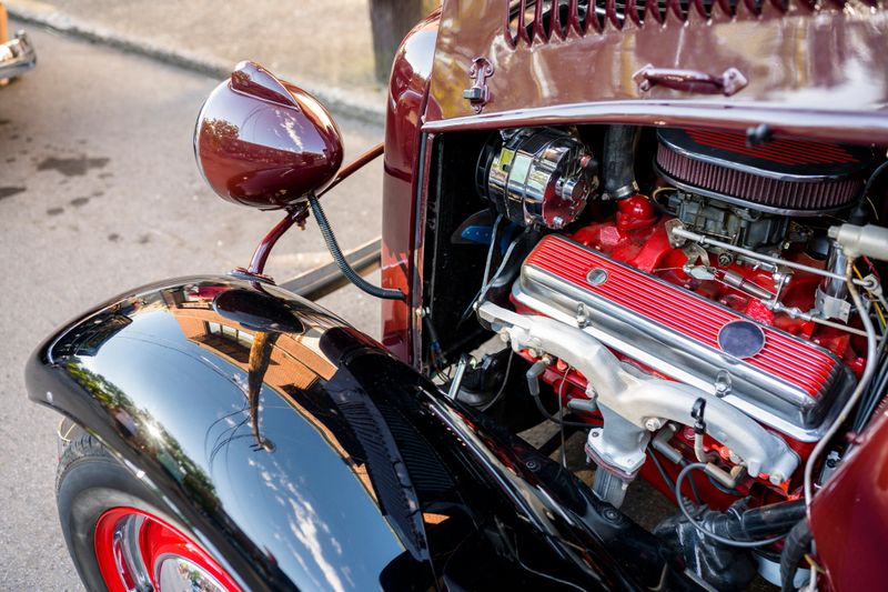 Elegant stylish black old vintage retro car with large convex wings and headlights and open powerful engine standing on an improvised street exhibition of retro cars in a provincial town